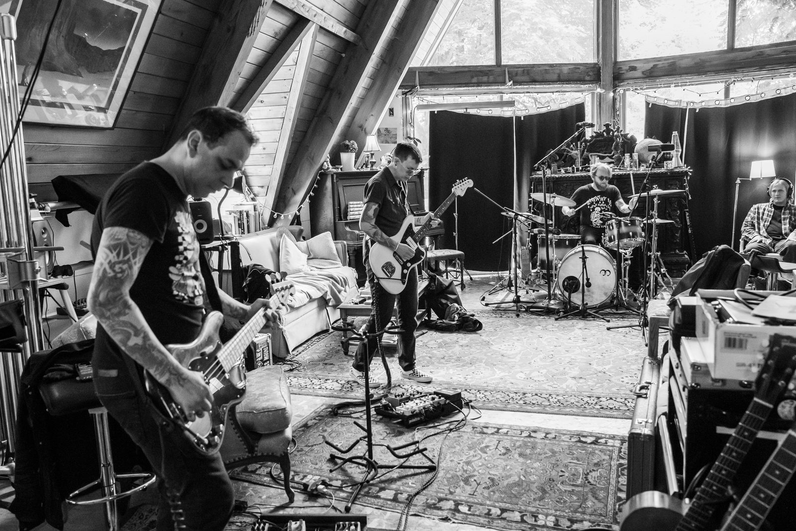 Tragic Lovers playing together in an A-frame recording studio: bass in the foreground, guitar and drums behind.